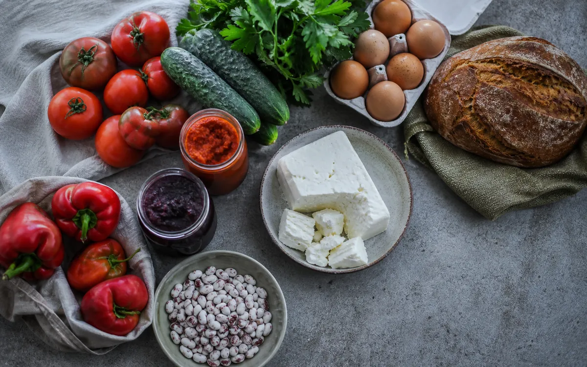 Bulgarian vegetables, eggs, white cheese, bread, lyutenitsa, jam and beans on a table